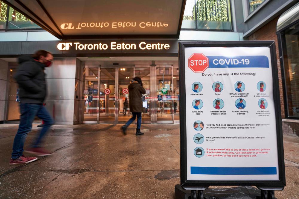(FILES) In this file photo people arrive at the entrance to the Toronto Eaton Centre in downtown Toronto, Ontario on November 23, 2020, the first day of a new lockdown in the city.