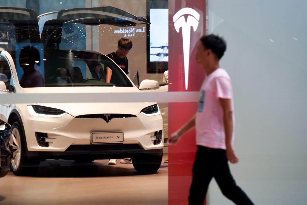 This file picture taken on July 4, 2018 shows a man visiting a Tesla showroom in Beijing. US electric auto maker Tesla said on April 22, 2019, it launched an investigation after a video circulating in China showed one of its cars suddenly burst into flames in a garage in Shanghai. — AFP