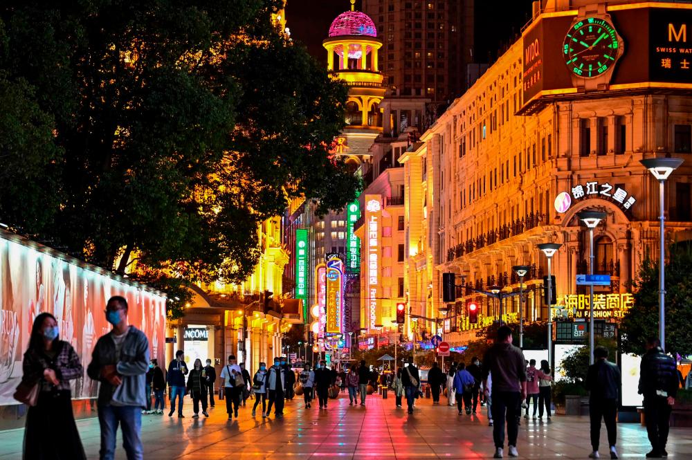 (FILES) In this file photo taken on October 12, 2022, people walk along a pedestrian street surrounded by shops and shopping malls in Shanghai. China’s economy grew 3.9 percent year-on-year in the third quarter, according to official data released on October 24, 2022, beating forecasts. AFPPIX