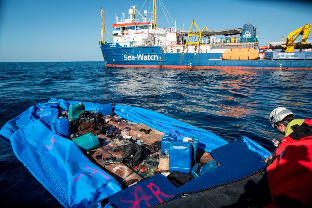 In this file photo taken on Jan 19, a Sea-Watch 3 crew member marks with spray paint a rubber boat that the NGO destroyed after rescuing 47 migrants that were onboard, during a rescue operation by the Dutch-flagged vessel (Rear) off Libya's coasts. — AFP