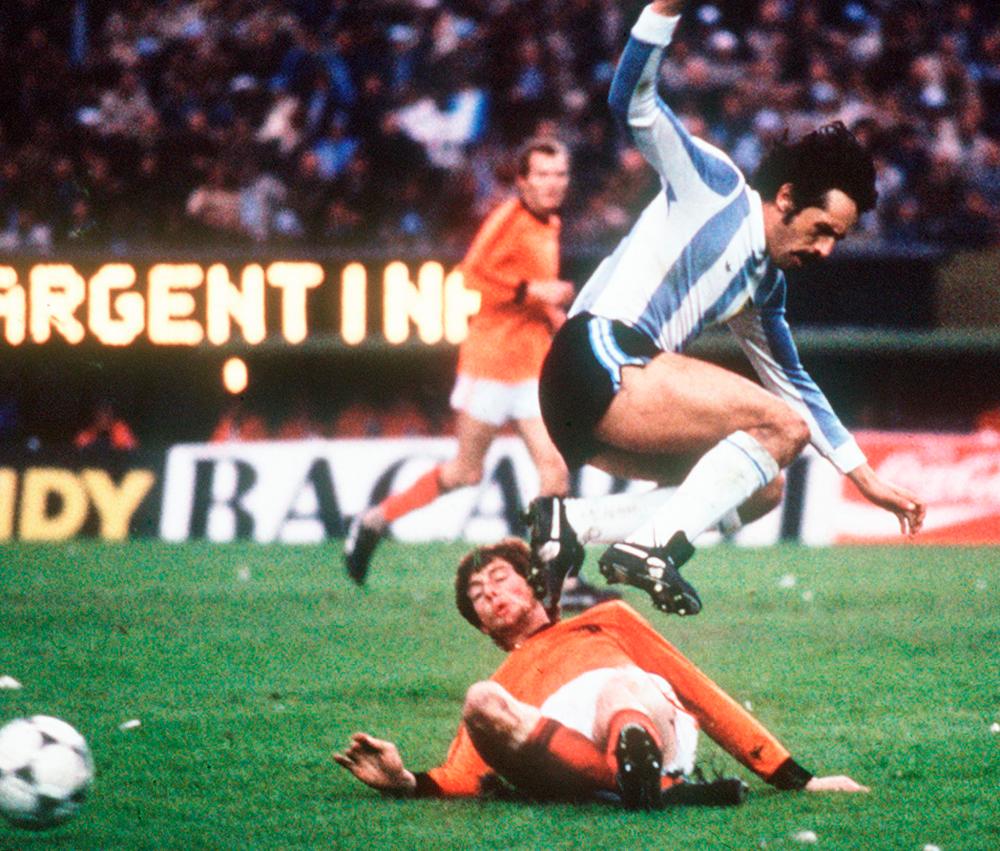 (FILES) In this file photo taken on June 25, 1978, Argentinian forward Leopoldo Luque jumps to avoid the tackle of Dutch defender Erny Brandts, in Buenos Aires, during the World Cup soccer final. Argentinian World Cup winner Leopoldo Luque died on February 15, 2021, of a heart attack while he was receiving treatment for COVID-19, hospital sources said. / AFP / STAFF