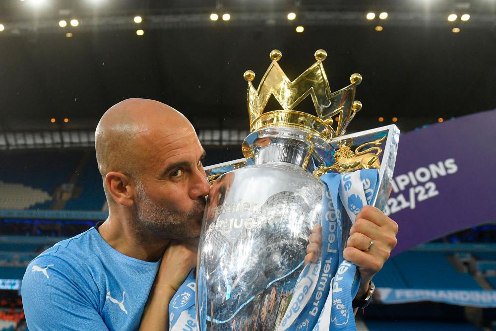 Pep Guardiola celebrates with the Premier league trophy on the pitch after the English Premier League football match between Manchester City and Aston Villa at the Etihad Stadium in Manchester, north west England, on May 22, 2022. AFPPIX