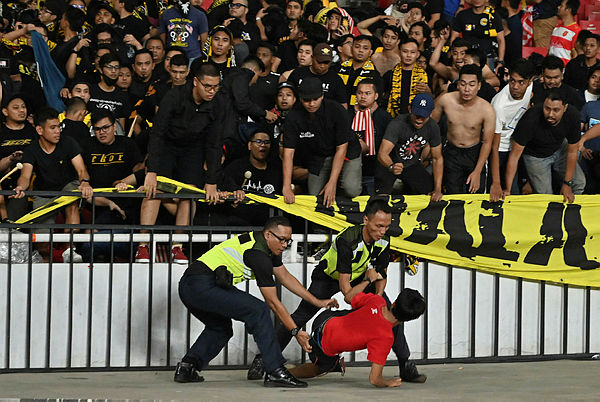 This file photo taken on September 5, 2019 shows policemen detaining a supporter of Indonesia next to supporters of Malaysia (in black) after an incident during their 2022 Qatar World Cup preliminary qualification round 2 football match at the Gelora Bung Karno stadium in Jakarta. — AFP
