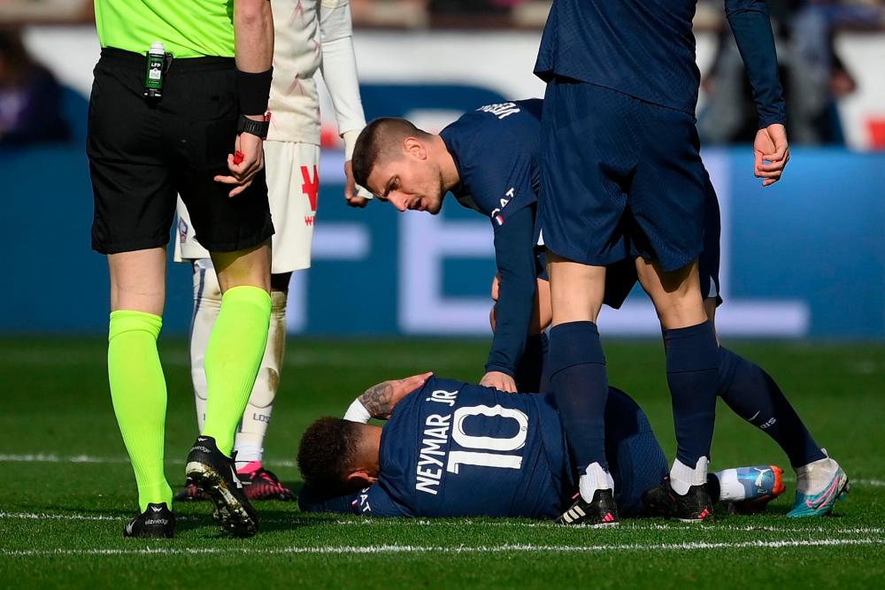 In this file photo taken on February 19, 2023 Paris Saint-Germain's Italian midfielder Marco Verratti (back) comforts Paris Saint-Germain's Brazilian forward Neymar lying on the pitch, injured following a contact with Lille's French midfielder Benjamin Andre (unseen) during the French L1 football match between Paris Saint-Germain (PSG) and Lille LOSC at The Parc des Princes Stadium in Paris. AFPPIX