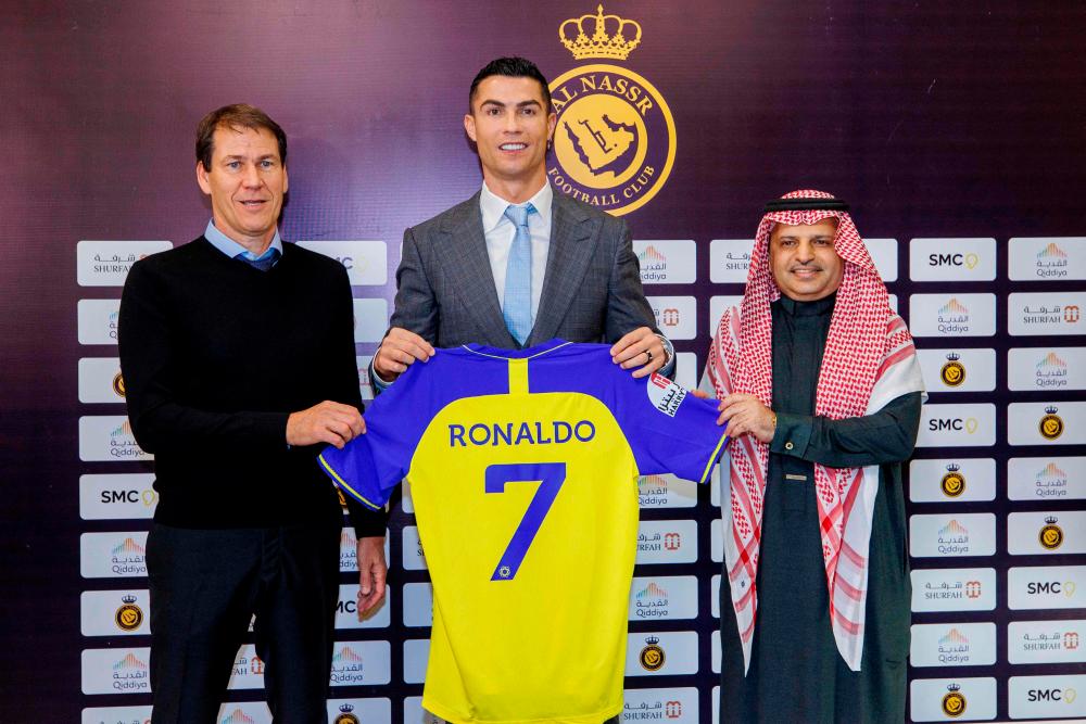 In this file handout picture released by Saudi Arabia’s al-Nassr football club on January 03, 2023 Portugal’s forward Cristiano Ronaldo poses with the club’s number seven jersey alongside Al-Nassr’s French coach Rudi Garcia (L) and club president Musalli Al-Muammar during a press conference at the Mrsool Park Stadium in Riyadh/AFPPix