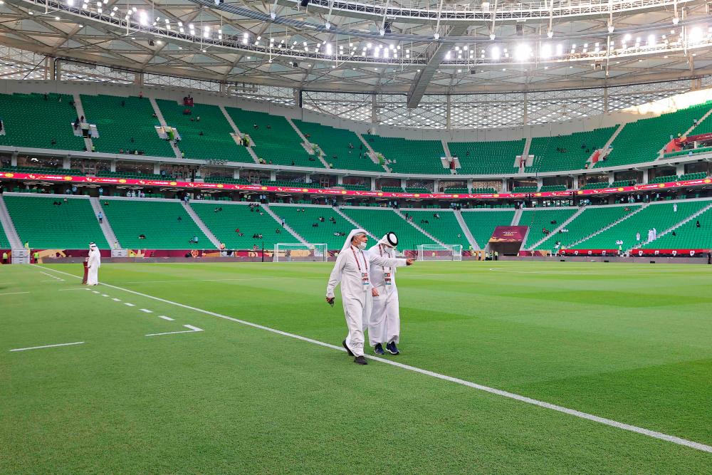 (FILES) In this file photo taken on October 22, 2021 Qatari officials walk on the pitch ahead of the Al-Thumama Stadium in the capital Doha. Qatar World Cup ticket sales were launched at reduced prices on January 19, 2022 with residents and migrant workers able to attend games for just $11 as concerns persist over Covid-19. AFPPIX