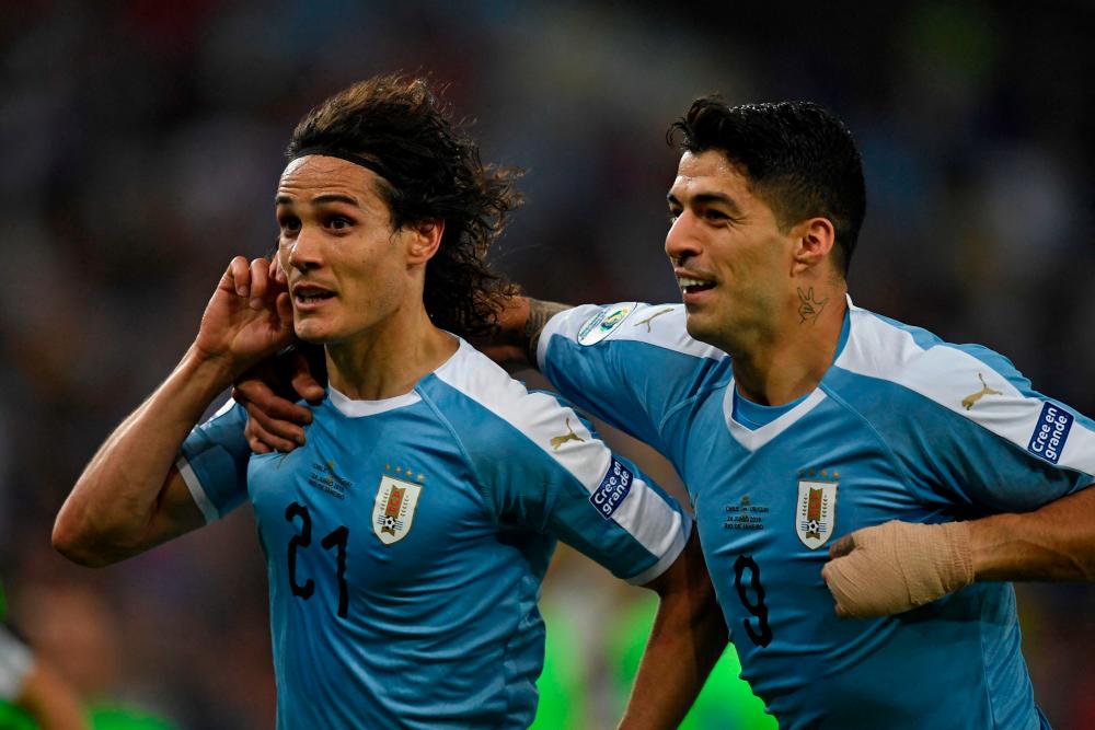 In this file photo taken on June 24, 2019, Uruguay’s Edinson Cavani (L) celebrates with teammate Luis Suarez after scoring against Chile during their Copa America football tournament group match at Maracana Stadium in Rio de Janeiro, Brazil. AFPPIX