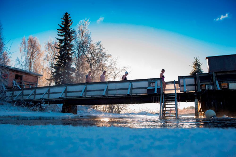 $!FILES) In this file photo taken on January 15, 2017 Finns take a dip in an unfrozen hole of water after a sauna session in Vaasa, as air temperature is -17°C and water is +1°C. The sauna tradition in Finland’s has been inscribed on the UNESCO Lists of Intangible Cultural Heritage on December 17, 2020. AFP / OLIVIER MORIN