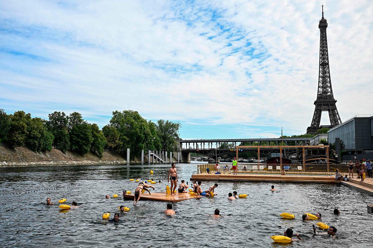 (FILES) People swim at the Grenelle safe bathing site on the Seine river on its opening day, in front of the Eiffel Tower in Paris on July 5, 2025. - JULIEN DE ROSA / AFP