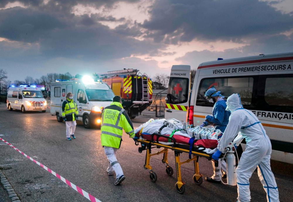 In this file photograph taken on March 29, 2020, emergency medical personnel carries a patient affected with coronavirus (Covid-19) from a military hospital to an ambulance before being transported aboard a medicalised TGV (high-speed train) to be evacuated towards hospitals of other French regions, in Mulhouse, eastern France, amid the spread of the COVID-19 (new coronavirus) pandemic. AFPPIX