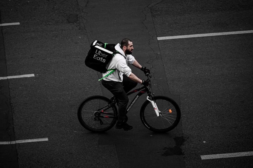 (FILES) In this file photo taken on April 20, 2020 A delivery man working for Uber Eats rides a bicycle in Paris, on the thirty-fifth day of a lockdown in France aimed at curbing the spread of the COVID-19 disease, caused by the novel coronavirus. AFP / Philippe LOPEZ