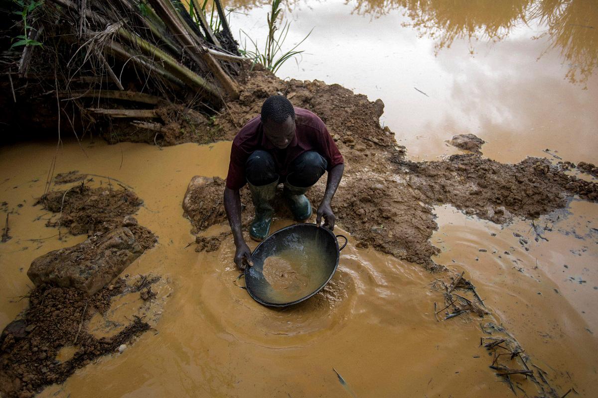 A Galamseyer, an illegal gold panner, washes the soil to check as he looks for speck of gold, in Kibi area, southern Ghana on April 11, 2017. - AFPpix