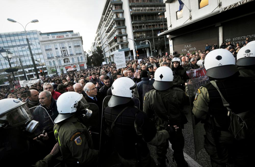 In this file photo taken on Nov 17, 2011, Greek anti-junta resistance veterans argue with police who block the road during a protest march marking the anniversary of the 1973 students uprising against military junta, in Athens. — AFP