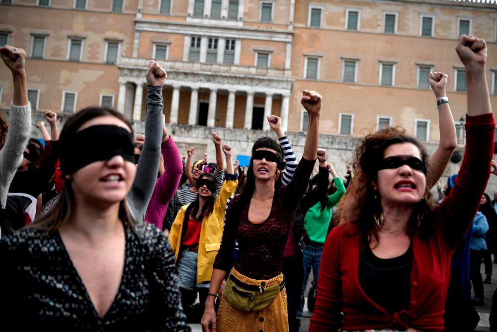 (FILES) In this file photo taken on December 22, 2019, female activists perform a choreography originated in Chile, and inspired by the Chilean feminist group Las Tesis, to protest against gender violence and patriarchy in front of the Greek parliament at Athens’ Syntagma Square. AFPPIX