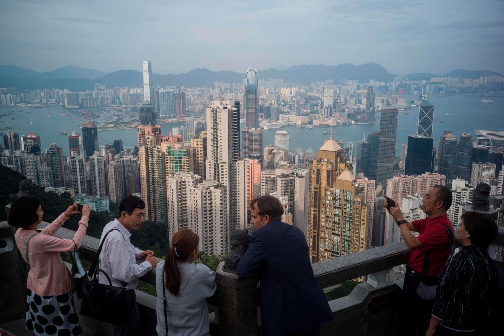 In this file photo taken on October 30, 2019 tourists chat and take photos as they visit Victoria Peak in Hong Kong. AFPPIX