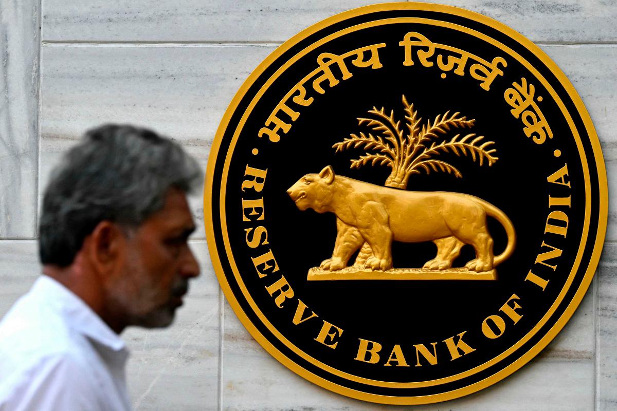 (FILES) A pedestrian walks past the Reserve Bank of India (RBI) logo outside its headquarters in Mumbai on February 7, 2025. - Indranil Mukherjee / AFP