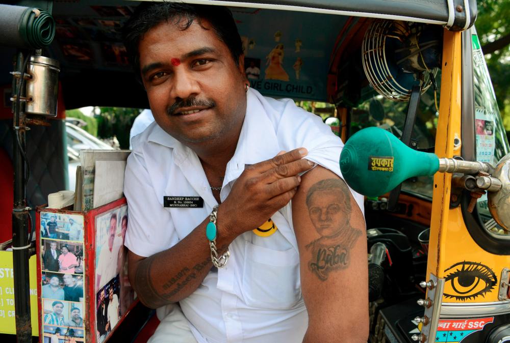 In this file photo taken on September 22, 2017 Sandeep Bacche, an Indian rickshaw driver and fan of Bollywood actor Sanjay Dutt, poses for a picture in Mumbai. A Bollywood actor’s face tattooed on his arm, Sandeep Bacche’s devotion shocks few in India where stars enjoy semi-divine status. / AFP / Punit PARANJPE