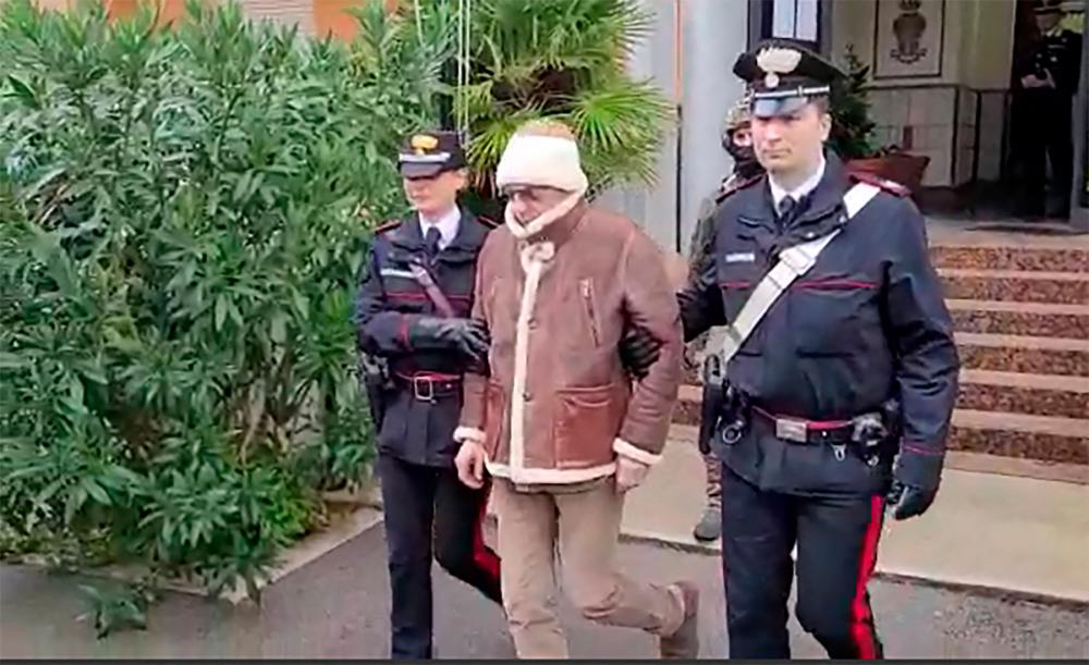 This handout video grab taken and released by the Italian Carabinieri Press Office on January 16, 2023 shows the transfer of Italy’s top wanted mafia boss, Matteo Messina Denaro (C) from the Carabinieri police station of San Lorenzo in Palermo, to an undisclosed location, following his arrest in his native Sicily on January 16, 2023 after 30 years on the run/AFPPix