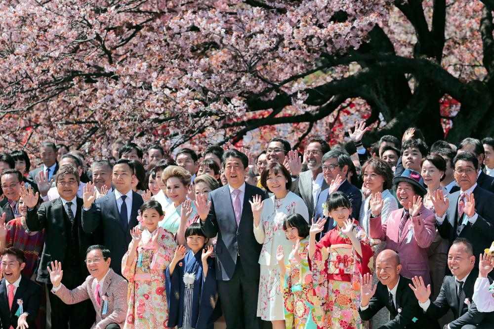 In this file photo taken on April 13, Japanese Prime Minister Shinzo Abe (centre L) and his wife Akie (center R) pose for pictures with their guests during his cherry blossom viewing party at a park in Tokyo. — AFP