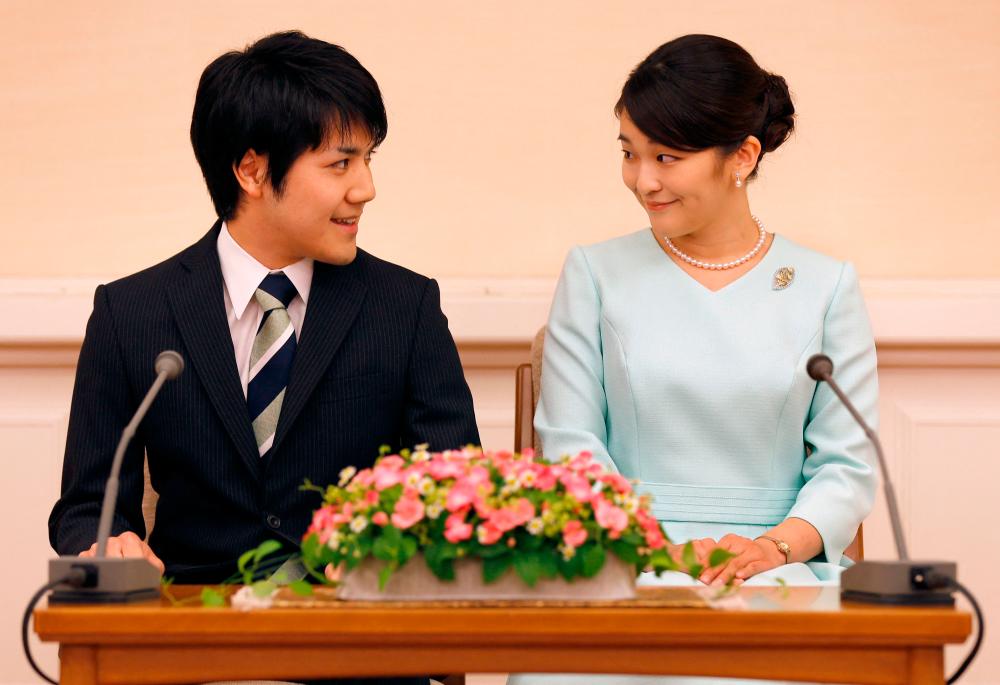This file photo taken on September 3, 2017 shows Japan's Princess Mako (R), the eldest daughter of Prince Akishino and Princess Kiko, looking at her fiancée Kei Komuro (L), as they meet the media during a press conference to announce their engagement at the Akasaka East Residence in Tokyo. Japan's Princess Mako is expected to marry her university sweetheart Kei Komuro on October 26, 2021, but she will forego traditional rites and will not take a usual payment given to royal women marrying commoners. Shizuo Kambayashi / POOL / AFPPix