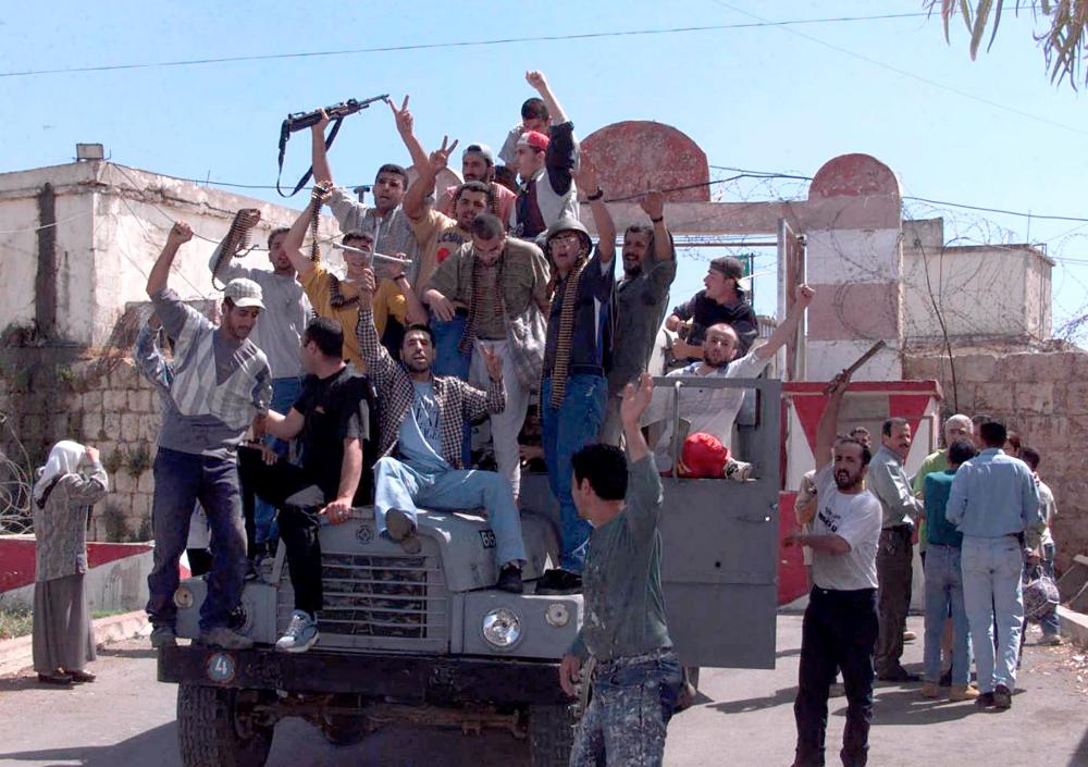 (FILES) A file photo taken on May 23, 2000 shows Lebanese prisoners celebrating atop a South Lebanon Army (SLA) truck at Khiam prison after a crowd of people stormed the South Lebanon Army-run (SLA) Khiam prison in southern Lebanon, setting all prisoners, some of whom had been held by Israel for over 10 years without trial, and its allied militia free. Twenty years after the withdrawal of Israeli forces from Lebanon, Hezbollah still enjoys wide support among youth regaled with tales of the Shiite group ending 22 years of Israeli occupation. The movement, also popular for its social services helping the poor, continues to leverage the memory of this era to mould a new generation of loyalists gearing up to join its regional operations. — AFP