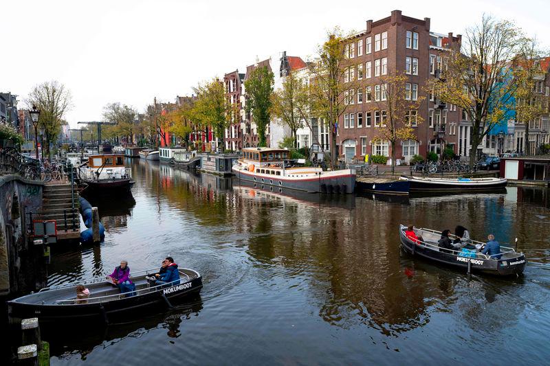 People navigate small boats on the Lekkersluis canal in Amsterdam on October 23, 2024, as the city launches its 750th anniversary celebrations. - AFPPIX