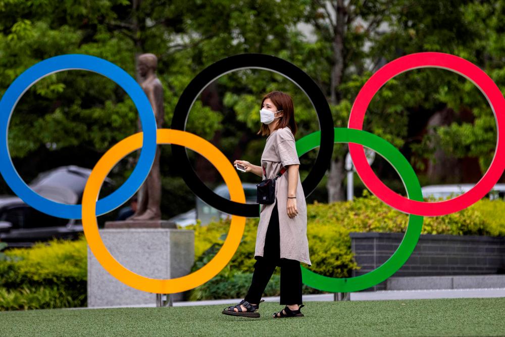 (FILES) In this file photo taken on June 3, 2021, a woman stands in front of the Olympic rings in Tokyo. The journey to this year's Olympic Games has been like no other. After a historic pandemic postponement, organisers refused to pull the plug, despite infection risks, travel restrictions and persistent public opposition. - AFP