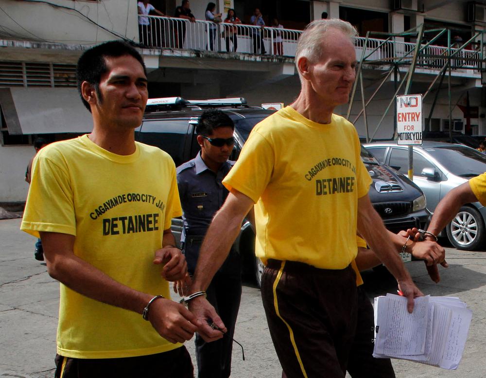 This file photo taken on June 16, 2015 shows Peter Scully of Australia (R), accused of raping and trafficking two girls in the Philippines, leaving the court handcuffed to another inmate (L) after his arraignment in Cagayan de Oro City, on the southern Philippine island of Mindanao. AFPPIX