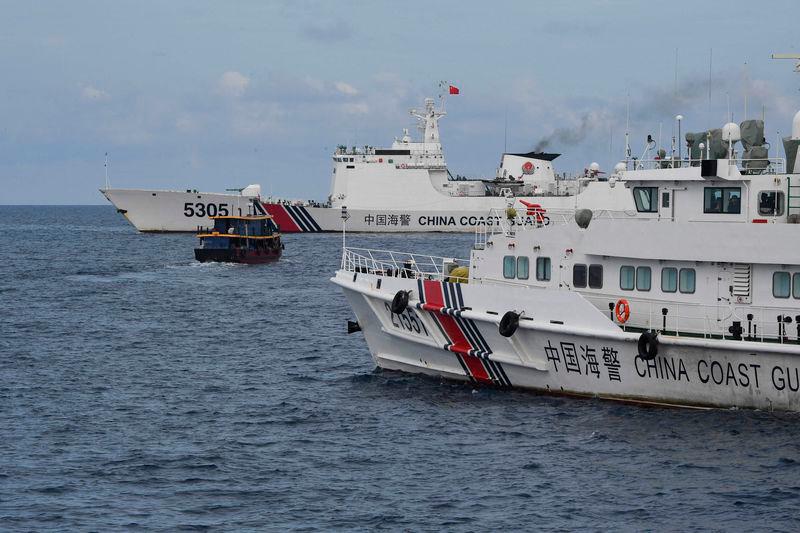 Chinese coast guard ships (L and R) corralling a Philippine civilian boat chartered by the Philippine navy to deliver supplies to Philippine navy ship BRP Sierra Madre in the disputed South China Sea - AFPpix