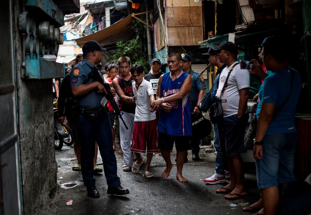 In this file photo taken on July 20, 2017, male residents are rounded up for verification after police officers conducted a large scale anti-drug raid at a slum community in Manila. AFPPIX
