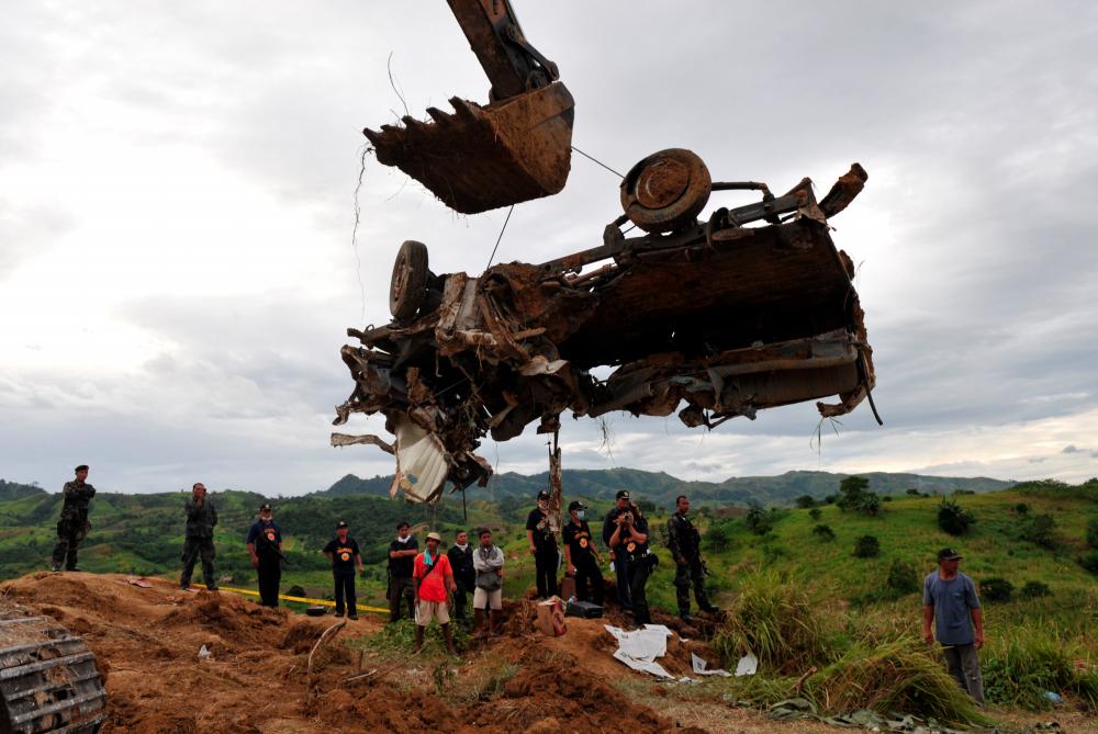 This file photo taken on Nov 25, 2009 shows a backhoe lifting a mangled vehicle unearthed from a shallow grave as investigators try to find more bodies, victims of a massacre after gunmen shot at least 22 people in Ampatuan town, Maguindanao province. — AFP