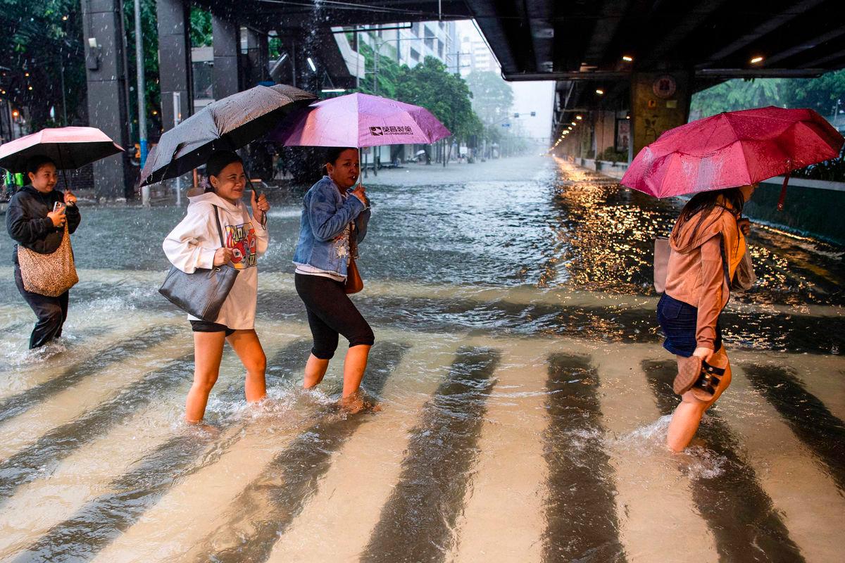 A file photo taken on July 22, 2025, shows pedestrians wading through a flooded street in Manila. - AFP