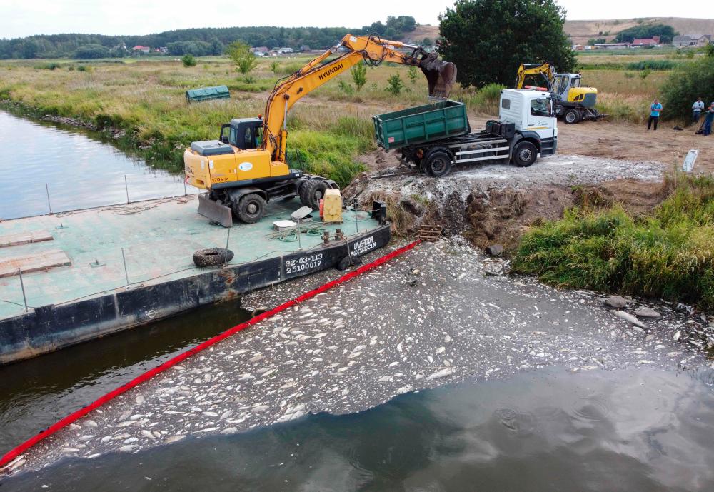 (FILES) In this file photo taken on August 15, 2022 a floating damm used to encircle dead fish on the river Oder and an escavator to remove them are pictured in Krajnik Dolny, north-western Poland. AFPPIX