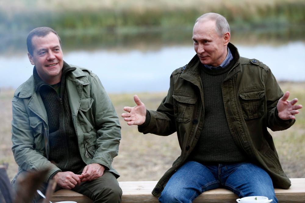 In this file photo taken on September 10, 2016 Russia's President Vladamir Putin (R) gesture as Russia's Prime Minister Dmitry Medvedev looks on during a visit to Ilmen Lake, near Novgorod. - AFP