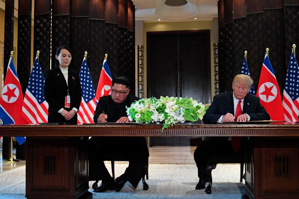 This file photo taken on June 12, 2018 shows US President Donald Trump (R) and North Korea’s leader Kim Jong Un (2nd L) signing documents as the North Korean leader’s sister Kim Yo Jong (L) looks on at a signing ceremony during their historic US-North Korea summit at the Capella Hotel on Sentosa island in Singapore. — AFP