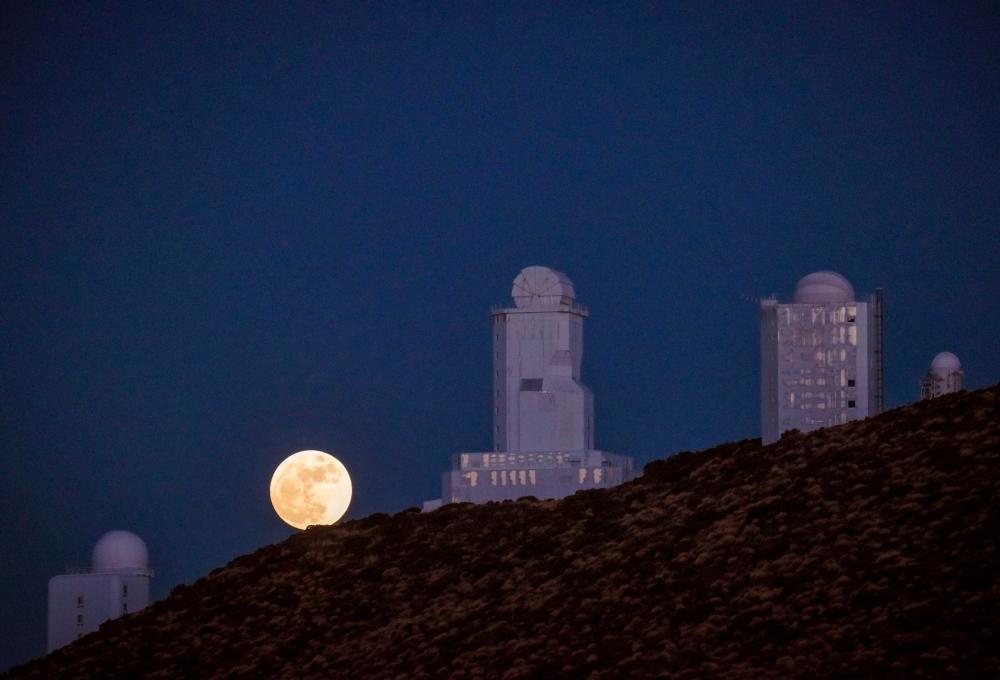 In this file photo taken on Dec 13, 2016 the full moon is seen behind telescopes of the Spain's Institute of Astrophysics of the Canary Islands, in the National Park of El Teide, on the Spanish canary island of Tenerife on December. A team of international astronomers has discovered a new solar system with a super-Earth planet that could be habitable, a Spanish astrophysicist who led the research said today. If researchers find the conditions are right on the planet known as GJ 257d, it will become the nearest confirmed habitable world, said Rafael Luque of Spain's Institute of Astrophysics of the Canary Islands. — AFP
