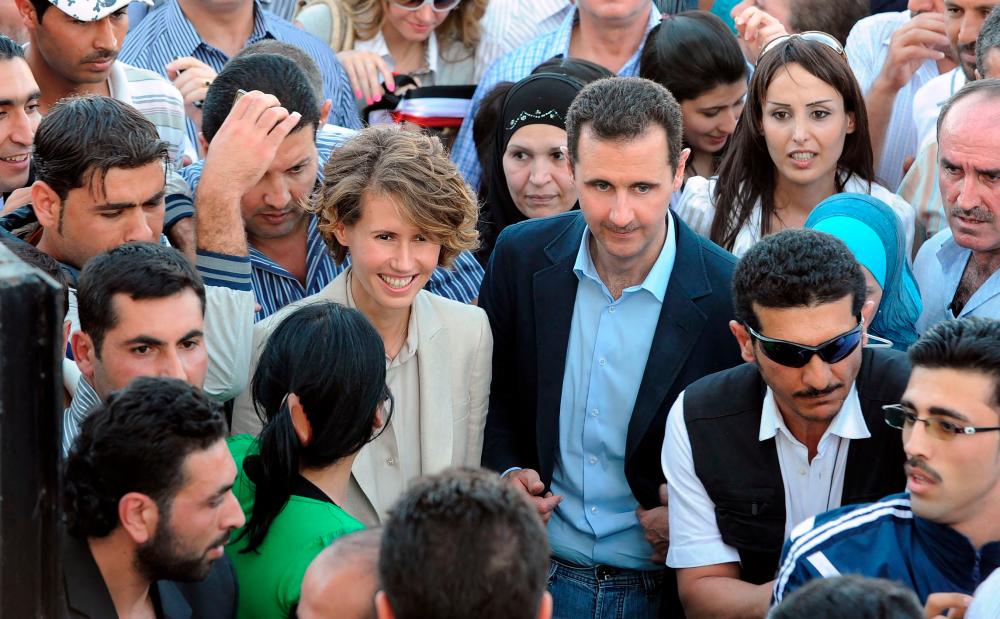 (FILES) In this file photo taken on June 30, 2011, Syrian President Bashar al-Assad (C-R) and First Lady Asma al-Assad (C-L) arrive at Al-Jalaa Stadium in Damascus to meet with regime supporters who made the biggest Syrian flag as a deadly crackdown continued on democracy protests across the country. -AFP
