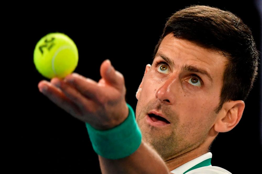 (FILES) In this file photo taken on February 21, 2021 Serbia's Novak Djokovic serves against Russia's Daniil Medvedev during the men's singles final on day fourteen of the Australian Open tennis tournament in Melbourne. AFPPIX