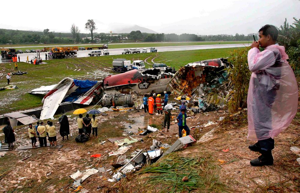 Workers and officials inspect the site of the One-Two-Go budget airline’s MD-82 passenger jet on the Thai resort island of Phuket, a day after the plane crashed as it tried to land in poor weather. — AFP