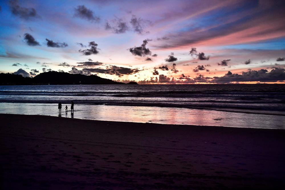 (FILES) In this file photo taken on September 30, 2020 shows a family on the beach at sunset in Patong beach in Phuket, which has seen a lack of tourists due to ongoing restrictions relating to the COVID-19 novel coronavirus. AFP / Lillian SUWANRUMPHA