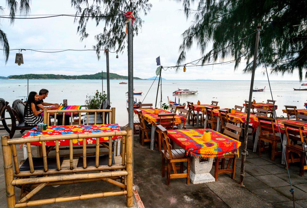 In this file photo taken on October 02, 2019, a couple sit at a restaurant on Raway beach on Phuket island. - AFP