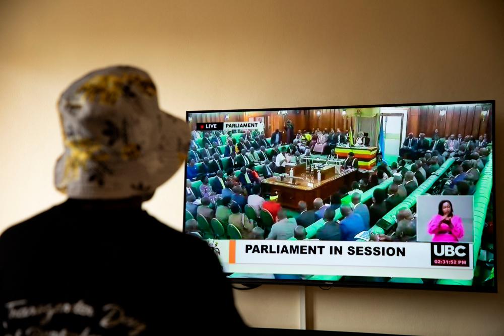 In this file photo taken on March 21, 2023 a Ugandan transgender woman who was recently attacked and currently being sheltered watches a TV screen showing the live broadcast of the session from the Parliament for the anti-gay bill, at a local charity supporting the LGBTQ Community near Kampala/AFPPix