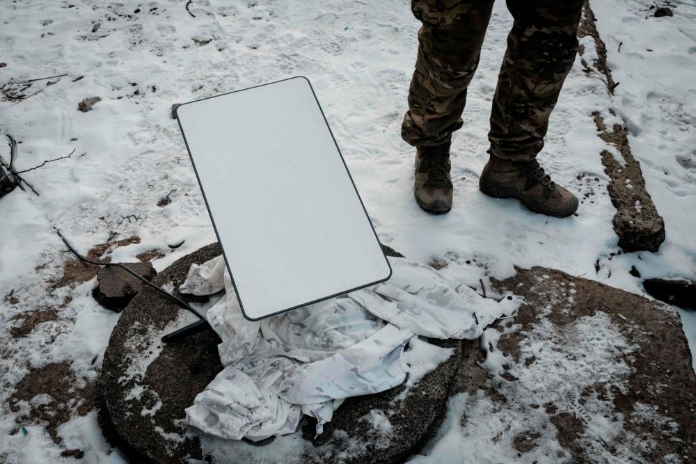 A Ukrainian serviceman stands next to the antenna of the Starlink satellite-based broadband system in Bakhmut on February 9, 2023, amid the Russian invasion of Ukraine. AFPPIX