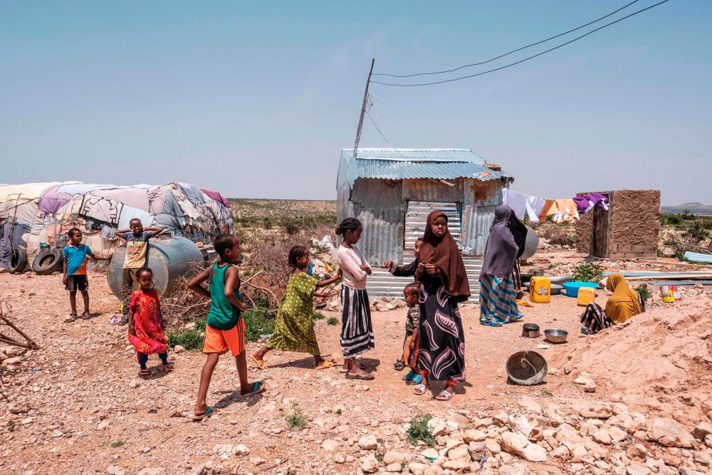 People stand outside of their homes in an informal settlement of internally displaced people in the outskirts of the city of Hargeisa, Somaliland, on September 16, 2021. AFPPIX