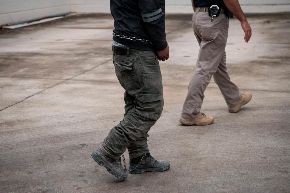 a shackled migrant in federal custody arrives for immigration hearings at the US federal courthouse in McAllen, Texas. — AFP