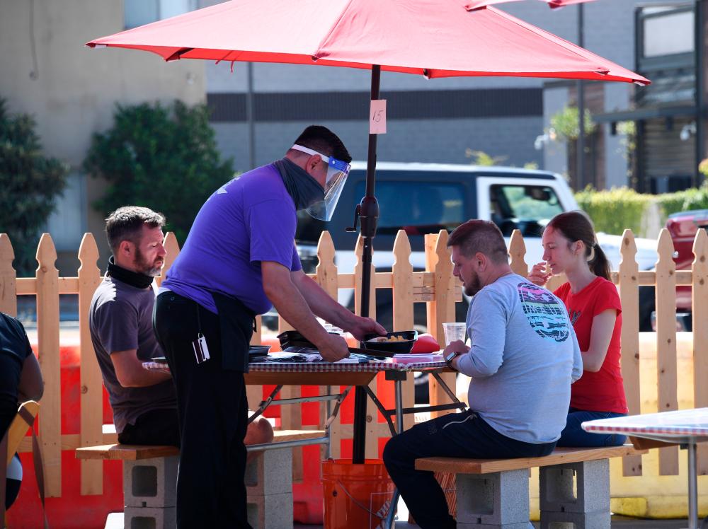 A waiter serves food to customers on the patio at Pann's, an iconic Los Angeles, California, restaurant and coffee shop, on July 4. Spending on services increased in the third quarter of 2020, thought it remained below its fourth quarter 2019 level. – AFPPIX