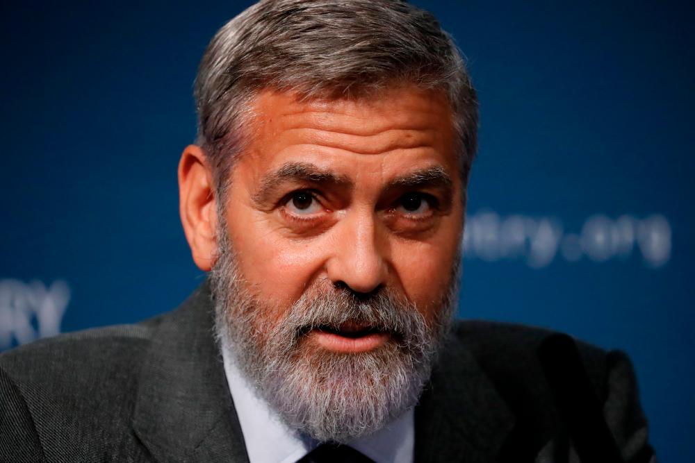 (FILES) In this file photo taken on September 19, 2019 US actor George Clooney takes part in a press conference in central London to present a report on atrocities in South Sudan. Pandemic hair getting out of control? Take a tip from George Clooney: the Hollywood style icon has revealed he trims his signature silver locks with a Flowbee –a quirky home-styling device that attaches to a vacuum cleaner. / AFP / Tolga AKMEN