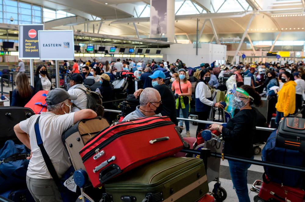 (FILES) In this file photo taken on May 28, 2021 travelers wait in line at John F. Kennedy (JFK) Airport ahead of Memorial day weekend in New York City. – AFP