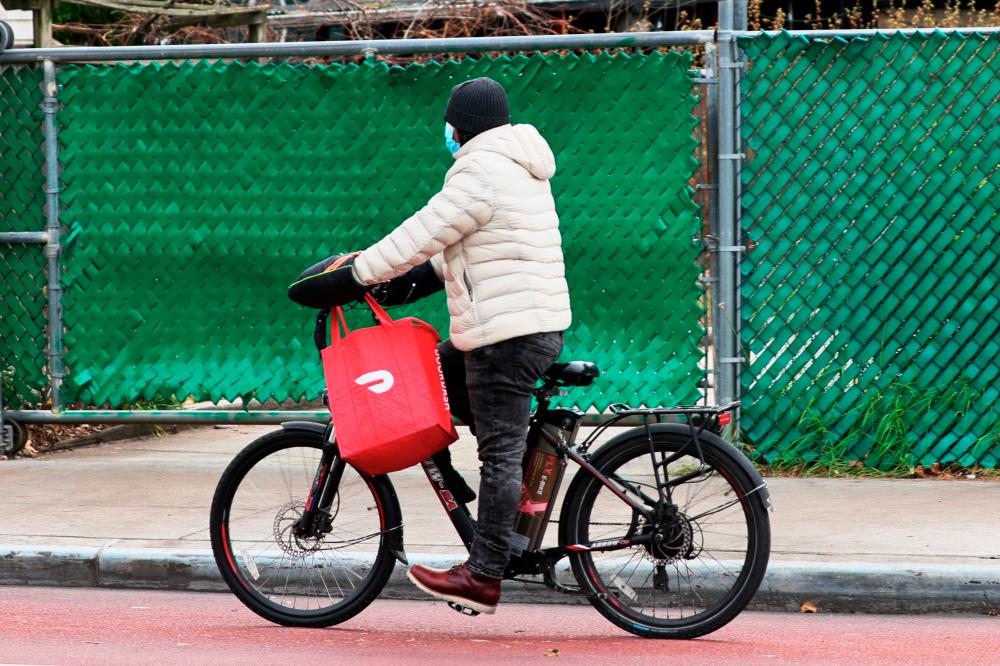 $!(FILES) In this file photo taken on December 4, 2020 A Doordash delivery person rides their bike on Church Avenue in the Flatbush neighborhood of Brooklyn in New York City. AFP / GETTY IMAGES NORTH AMERICA / Michael M. Santiago