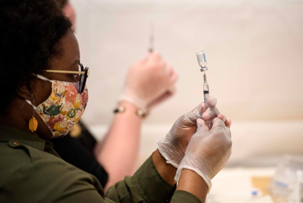 (FILES) In this file photo healthcare workers prepare a syringe with a vial of the J&amp;J/Janssen Covid-19 vaccine at a temporary vaccination site at Grand Central Terminal train station on May 12, 202 in New York City. – AFP